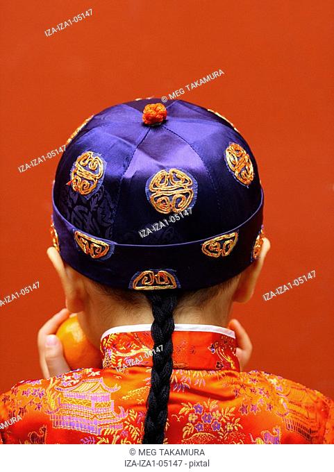Rear view of a boy holding an orange