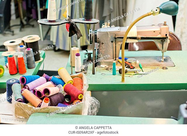 Spools of colorful threads and sewing machine in fashion design studio