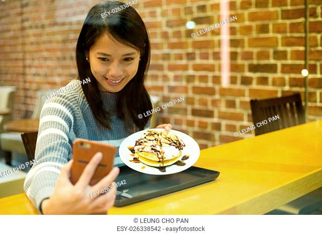 Woman take self photo with her dessert