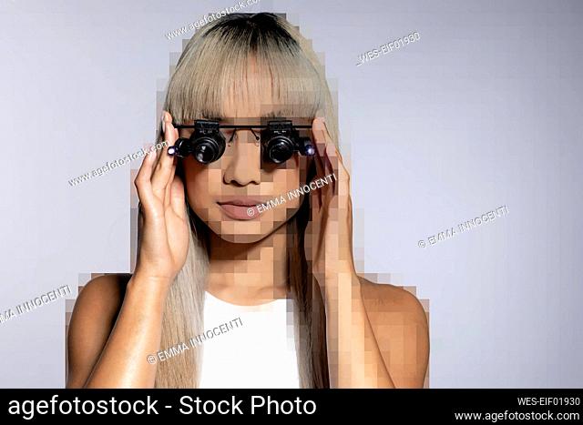 Pixelated young woman adjusting magnifying eyeglasses over white background