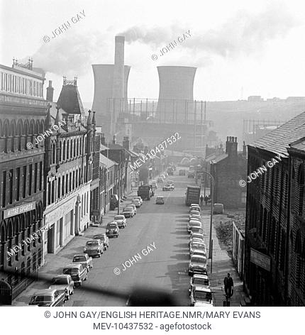 A view through the window of a train on the line north of Huddersfield station, looking west along Fitzwilliam Street with the gasometers and cooling towers...