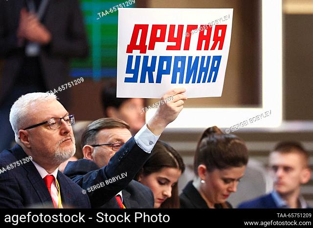 RUSSIA, MOSCOW - DECEMBER 14, 2023: A journalist holds up a sign with a message reading ""A Different Ukraine"" during an annual national live televised...
