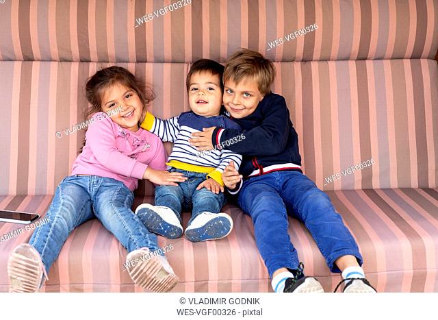 Portrait of three siblings sitting side by side