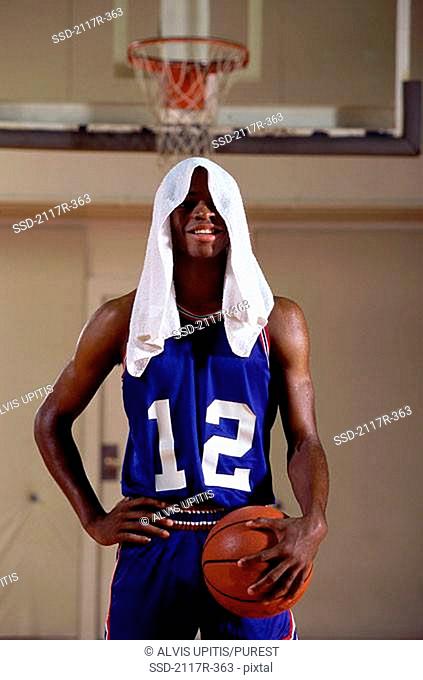 Young man standing holding a basketball with a towel on his head