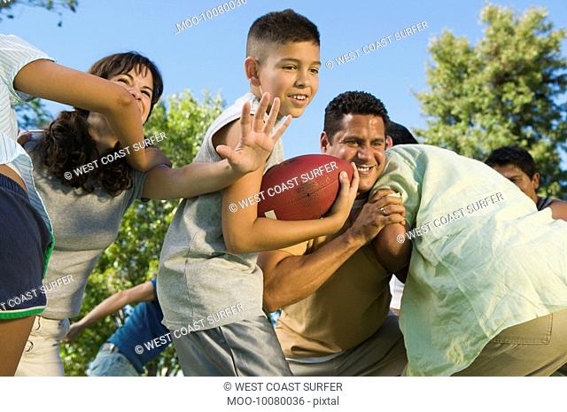 Boy 13-15 playing football with family