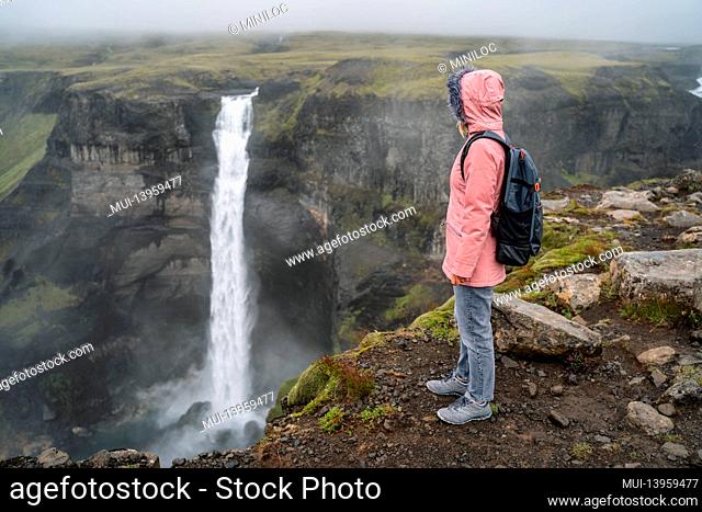 Woman with backpack enjoying Haifoss waterfall of Iceland Highlands