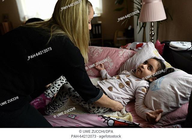 Mirella Kunzmann (l) places her daughter Aliana on a sofa in Bad Hersfeld, Germany, 2 December 2015. Five-year old Aliana is chronically ill with the incurable...