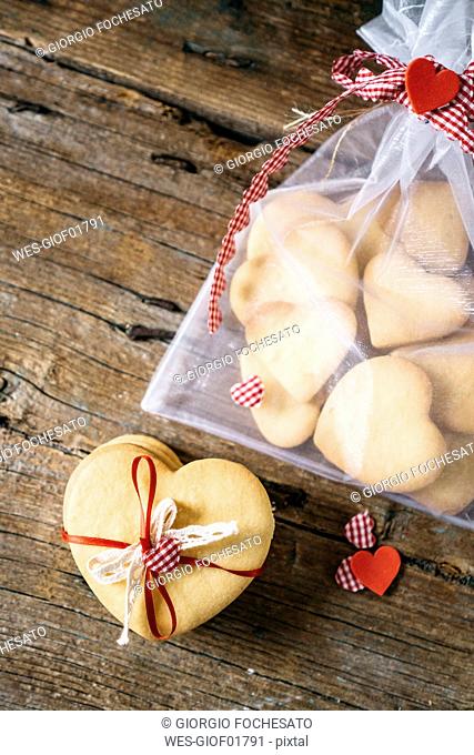 Stack of heart-shaped shortbreads tied with lace and ribbon and sachet with shortbreads on wood