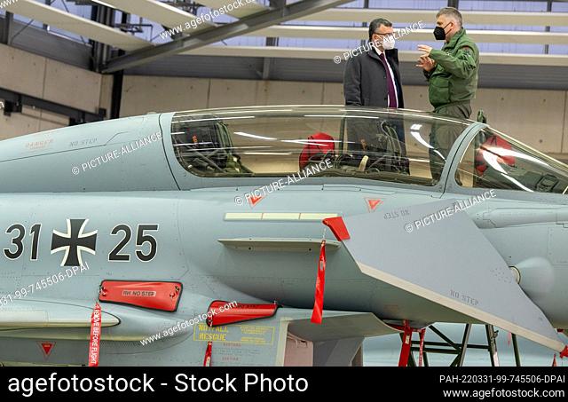 31 March 2022, Bavaria, Neuburg a.d.Donau: State Chancellor Florian Herrmann (l, CSU) has a Eurofighter Typhoon aircraft explained to him by Gordon Schnitger...