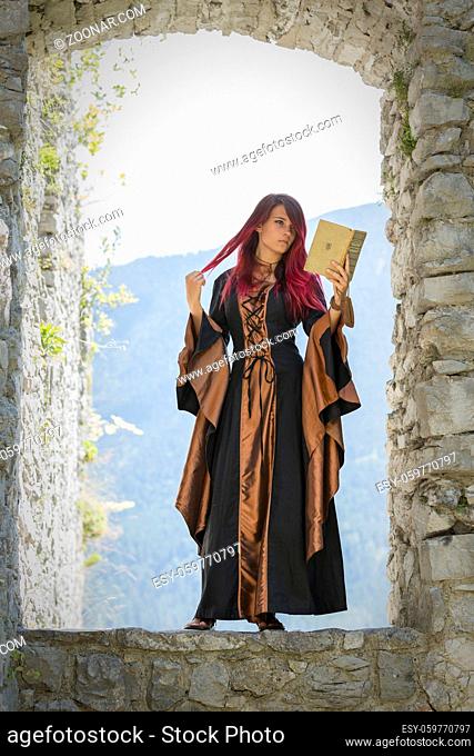 Junge rothaarige Frau in mittelalterlicher Kleidung liest ein Buch