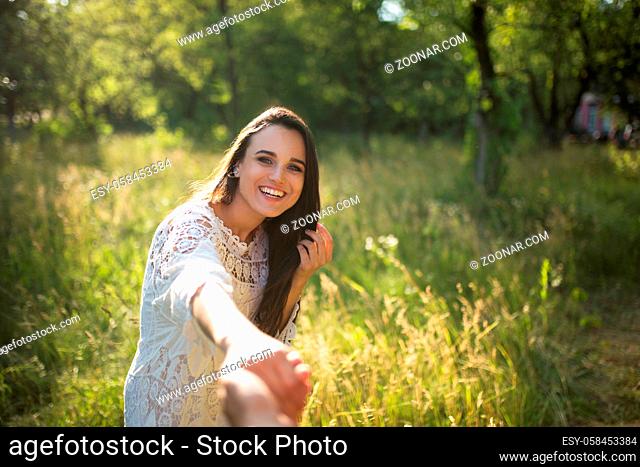 Lady enjoying nature with man she is holding by hand. Portrait of happy young woman holding her boyfriends hand taken from his point of view