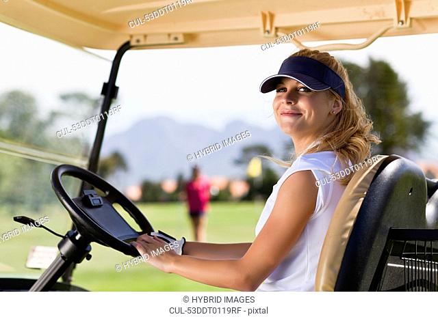 Woman driving golf cart on course