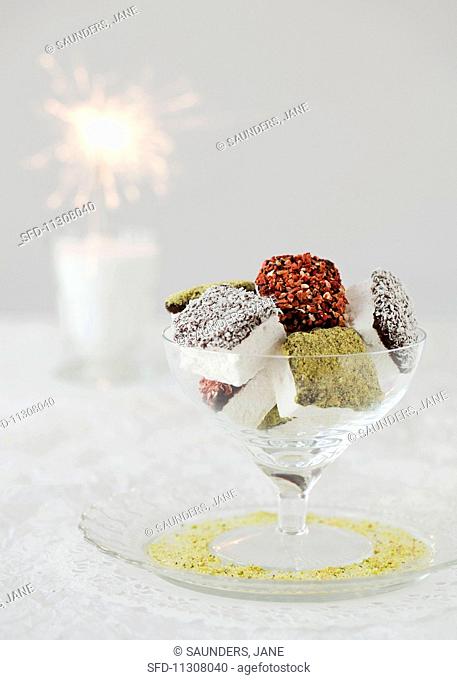 Chocolate-covered, coated marshmallows in a glass bowl with a sparkler in the background