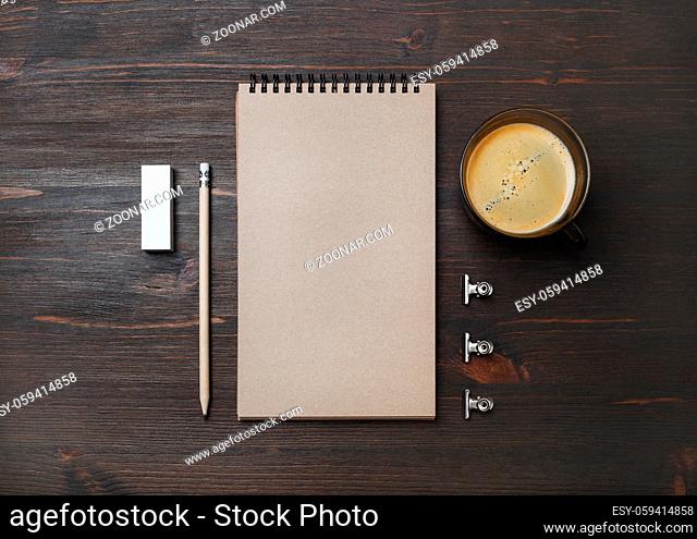 Coffee cup and blank stationery: kraft notebook, pencil and eraser on wood table background. Flat lay