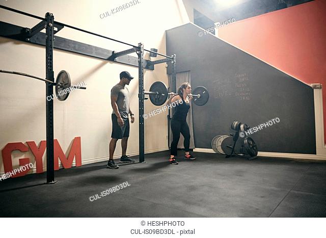 Woman in gym weightlifting using barbell