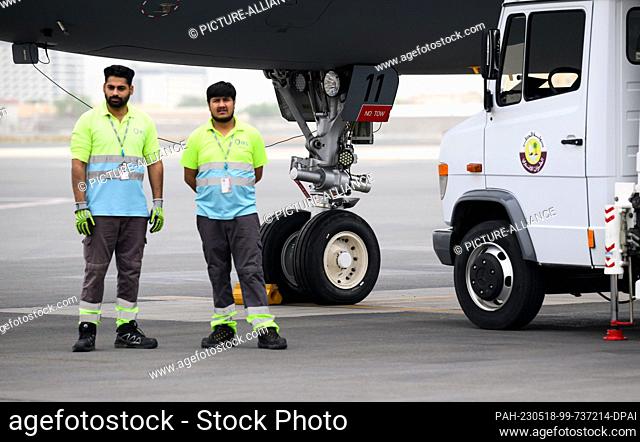 18 May 2023, Qatar, Doha: Airport employees stand at Doha International Airport next to the newly mounted front wheels of the Airbus A321 LR of the German Armed...