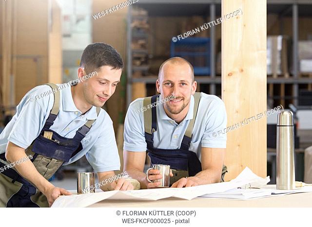 Two craftsmen with metal mugs talking