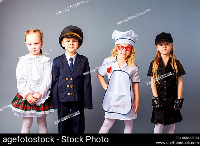 The group of young children dressed in uniforms of different professions stand on a gray background