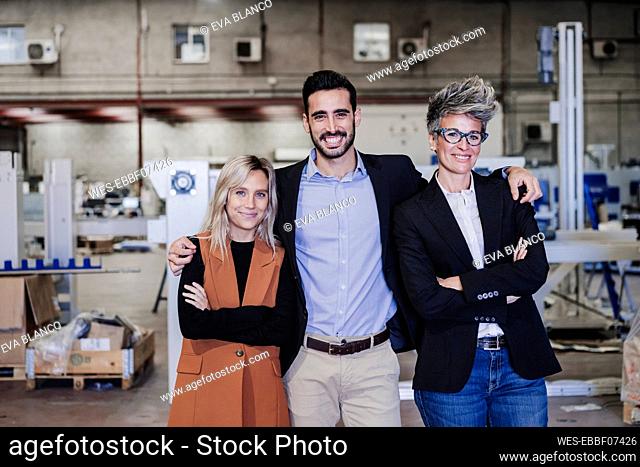 Happy businessman with colleagues standing at industry