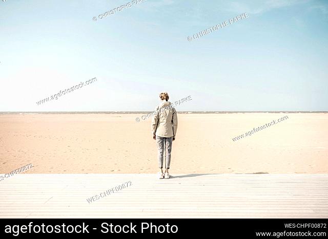 Woman standing on boardwalk at beach