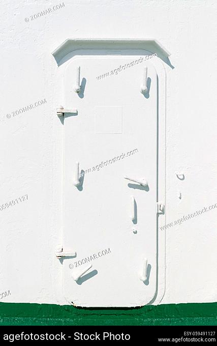 Narrow closed iron door with many locks on a ship painted in white color