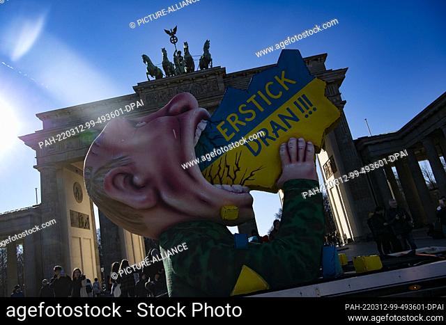 12 March 2022, Berlin: The Putin float of Düsseldorf carnival float maker Jacques Tilly drives past the Brandenburg Gate