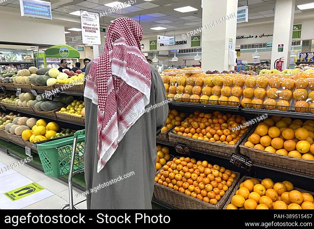 Impressions from Doha / Qatar on December 15th, 2022. Qataris, Arabs, locals in traditional clothing shopping in a supermarket in front of the fruit aisle with...
