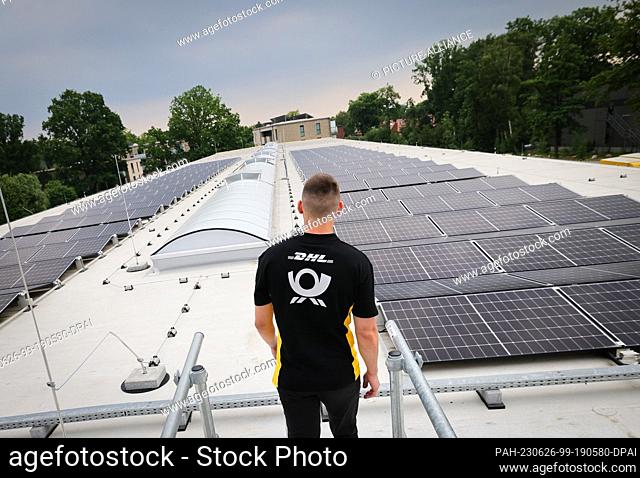 26 June 2023, Hamburg: An employee stands next to the photovoltaic system on the roof of the new DHL delivery base during a photo opportunity