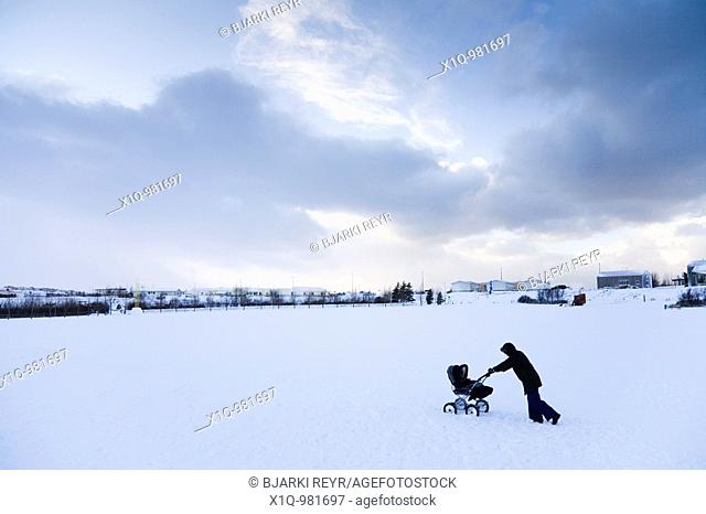 A woman walking with a pram in the snow  Hafnarfjordur, Iceland
