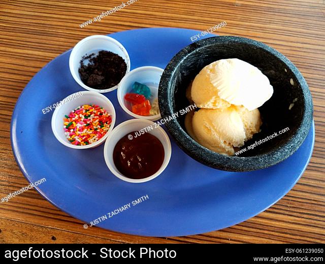 vanilla ice cream with sprinkles and chocolate on blue plate on wood table