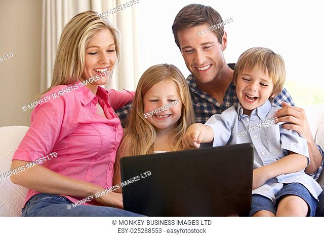 Family Using Laptop On Sofa At Home
