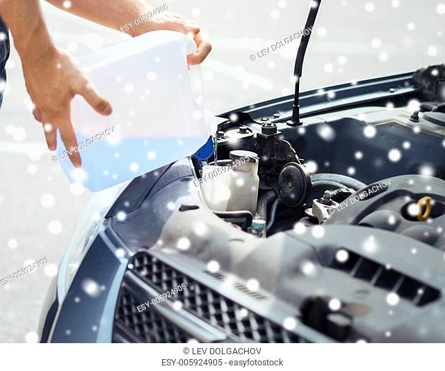 transportation and vehicle concept - man opening car bonnet and filling windscreen water tank with washing liquid