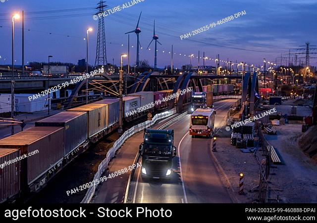 24 March 2020, Hamburg: A train loaded with containers and several trucks transport containers to the terminals of Hamburger Hafen und Logistik AG (HHLA)