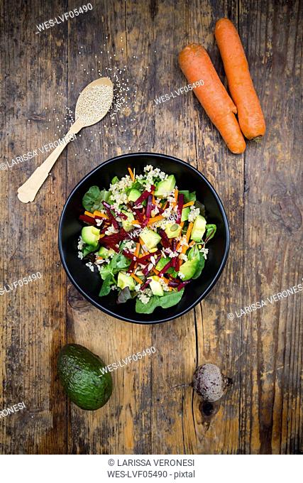 Bowl of autumnal salad with lettuce, carrots, avocado, beetroot, seeds, pomegranate and quinoa