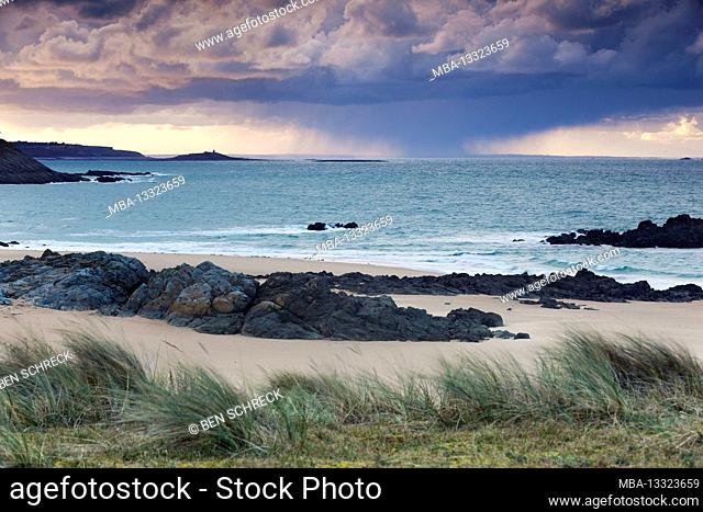 A storm is moving in the distance across the sea at Pleherel Plage, between Cap Frehel and the tidal island Ilot Michel. Brittany, France