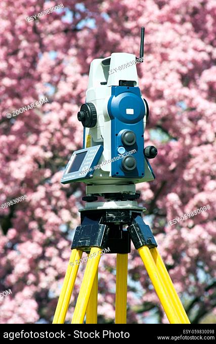 Spring surveying - theodolite against blosoming tree