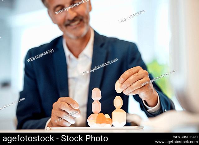 Smiling businessman stacking wooden rock in office