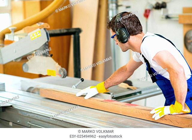 worker in a carpenter's workshop using drilling machine