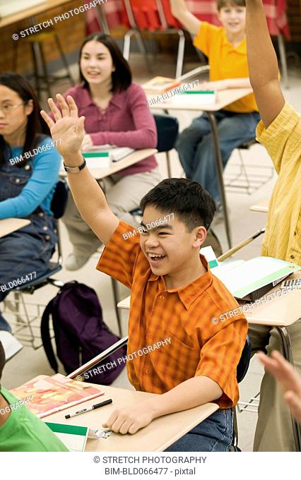 Asian student raising hand in classroom