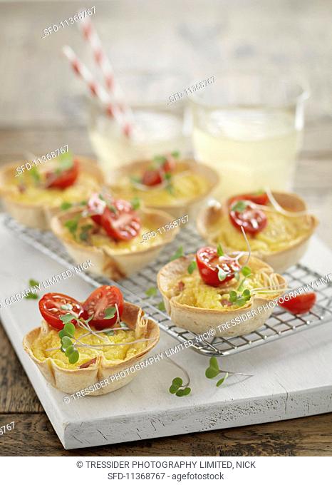 Scrambled eggs with diced ham in pastry cups garnished with tomatoes and cress