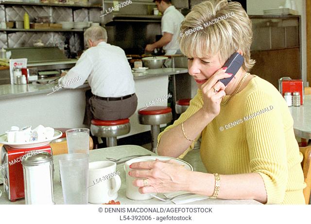 Female is on a cell phone in a restaurant where others can be bothered