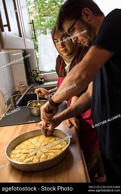 PRODUCTION - 10 May 2021, North Rhine-Westphalia, Minden: Hatice Bahadir (l) and Abdurrahman Bahadir prepare baklava together in their kitchen