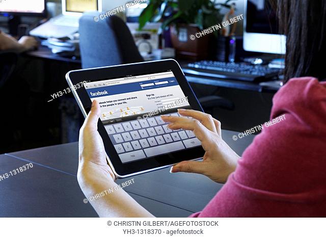 A woman using an iPad to check her Facebook page