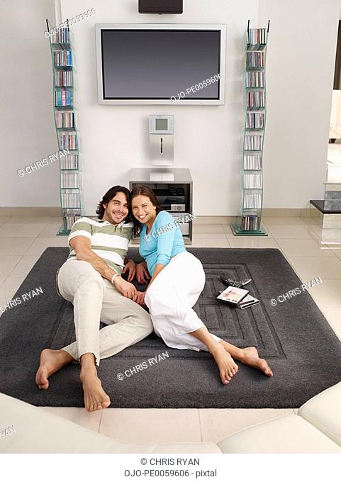Couple lying on rug in front of television