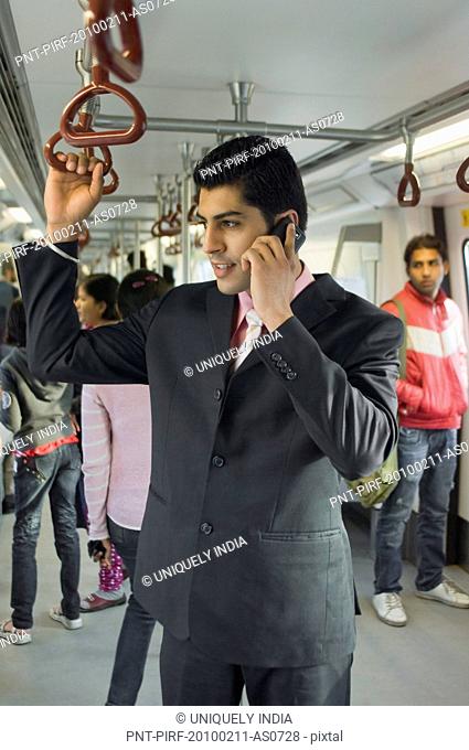 Businessman talking on a mobile phone in a subway train, New Delhi, India