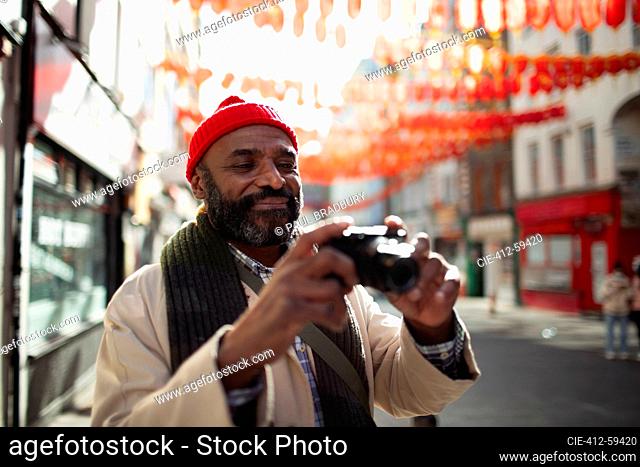 Male tourist with digital camera on street in Chinatown, London, UK