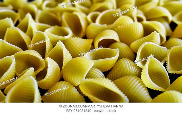 Raw Italian pasta conchiglie on a dark background. Shallow depth of field