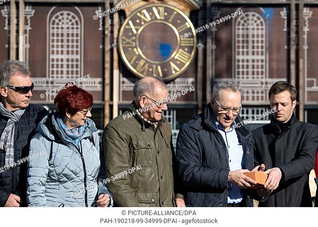 18 February 2019, Brandenburg, Potsdam: Visitors to an event are handed the first bricks for the entrance portal on the construction site of the garrison church...