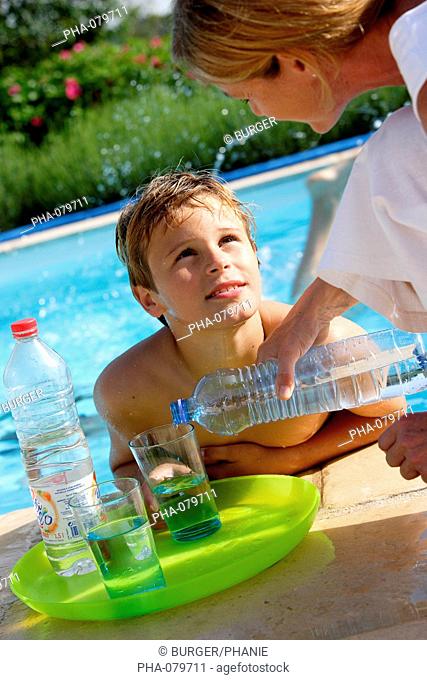 Child drinking a glass of water at the swimming pool