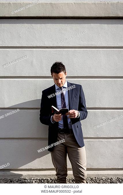Businessman outdoors looking in diary